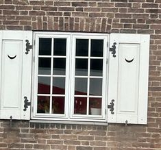 two white windows on the side of a brick building