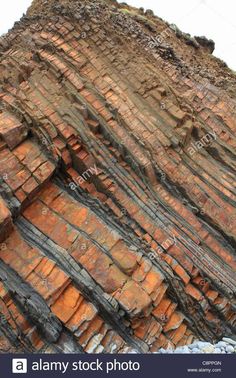 an old rock formation on the side of a mountain with red and brown colors - stock image