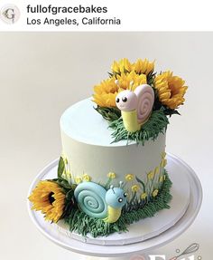 a white cake with sunflowers and snails on it