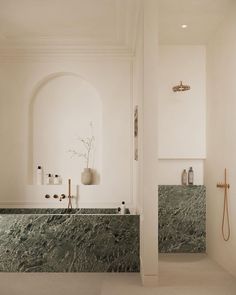 a bathroom with marble counter tops and white walls, along with an arched doorway leading to the shower