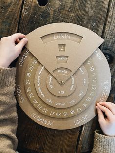 a person holding up a cardboard clock with writing on it and hands pointing at it