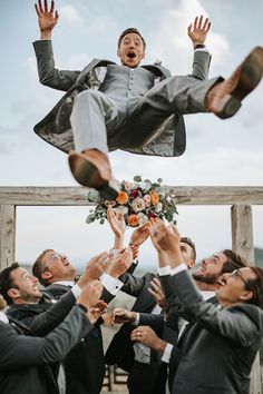 a group of people in suits and ties are holding up a man