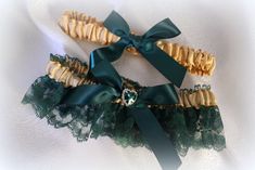 two garters with green bows and lace on white fabric, one has a jeweled brooch