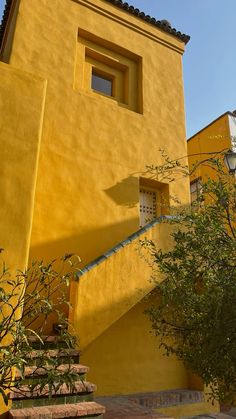 a yellow building with steps leading up to the top and bottom windows on each side