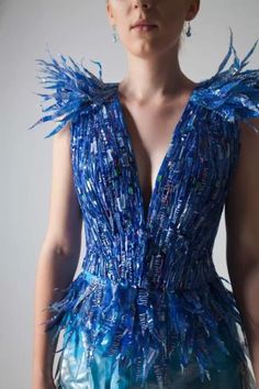 a woman wearing a blue dress with feathers on it