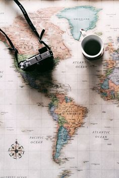 a map with a camera and a cup of coffee sitting on the table next to it