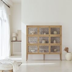 a wooden cabinet with glass doors in a white room