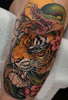 a tiger with a snake on its head and flowers around it's neck is shown