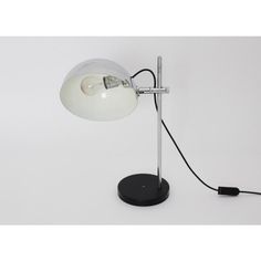 a white table lamp with a black base and an electric cord plugged into it