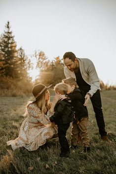 a man and two children are playing with each other in the grass while one child is holding his mom's hand