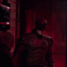 the dark knight in batman's costume standing next to a man with his hands on his hips