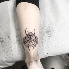 a ladybug tattoo on the leg of a woman's leg, with black dots