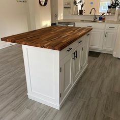 a large kitchen island in the middle of a room with white cabinets and wood counter tops