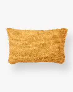 a mustard colored pillow on a white background