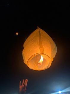 a hand reaching up to a lantern in the sky