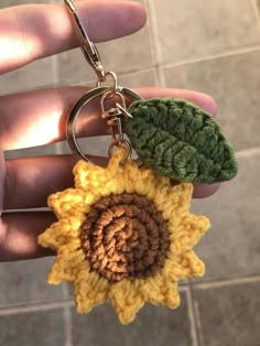 a crocheted sunflower keychain is being held by someone