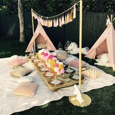 an outdoor party with pink and yellow decorations on the grass, including teepee tents