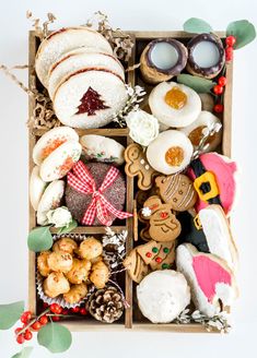 a wooden box filled with cookies and other holiday treats on top of a white table