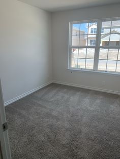 an empty room with carpeted floor and large window