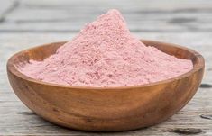 a wooden bowl filled with pink powder