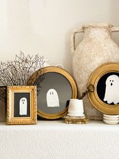 there are two framed pictures on the mantle with ghost decorations in front of them, and one has a spooky head