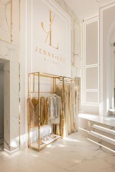 an elegant clothing store with marble floors and walls, featuring clothes on display in gold racks