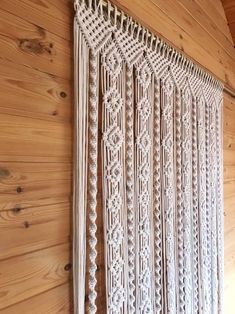 a white crocheted curtain hanging on the side of a wooden wall