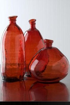 three red glass vases sitting on top of a table next to eachother