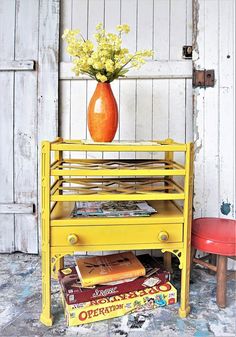 an orange vase with yellow flowers sitting on top of a yellow shelf next to books