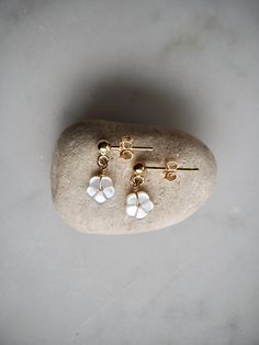 Delicate and dainty gold stud earrings with tiny white mother of pearl flower dangle. These sweet mop sakura flower stud earrings are lightweight and minimalist - the perfect everyday earrings.  14 k gold filled studs with 3mm ball. Comes with gold filled backs. The mop flower is 6mm.  Made using the highest quality USA and UK sourced materials. 📦 Eco-friendly packing I try my best to use as little plastic as possible in my packaging. Each order will arrive wrapped in a sweet eco-friendly and b Elegant Tiny Teardrop Earrings, White Pierced Earrings For Gift, White Pierced Earrings As A Gift, Dainty White Dangle Flower Earrings, White Pearl Drop Cluster Earrings For Anniversary, Dainty White Pearl Drop Bridal Earrings, White Sterling Silver Drop Cluster Earrings, Dainty Dangle Flower Earrings For Anniversary, Dainty Pearl Drop Flower Earrings