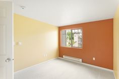 an empty room with orange walls and white carpet