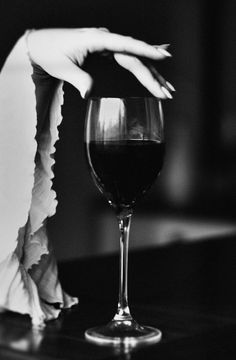 a woman's hand reaching for a glass of wine in black and white photo