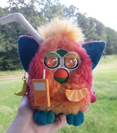 a hand holding a small stuffed animal with glasses on it's face and an orange drink in its mouth