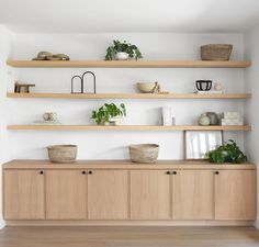 shelves with plants and baskets on them in a white living room, along with other items