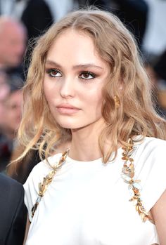 a close up of a woman with blonde hair and blue eyeshadow wearing a white dress