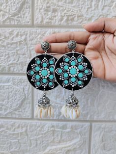 a pair of black and white earrings with turquoise stones in the shape of an elephant's head