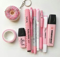 various pens, markers, and doughnuts sitting on a table next to each other