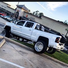 a white pickup truck parked on the side of a road next to a shopping center