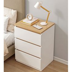 a night stand with a lamp on top of it next to a bed and nightstand