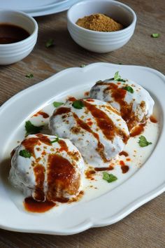 some food is on a white plate with sauce and seasoning in small bowls next to it