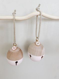 two wooden ornaments hanging from a white hook on a coat rack, with the letters m and n painted on them