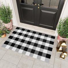 a black and white checkered door mat in front of two potted plants