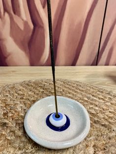 a blue and white bowl with a stick sticking out of it's center on a table