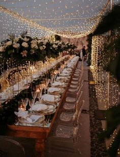 a long table is set up with white flowers and greenery for an elegant dinner