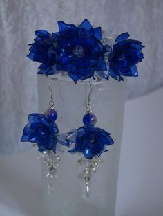 a pair of blue flower earrings sitting on top of a glass vase