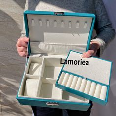 a person holding an open jewelry box with several compartments and the word lamorea written on it