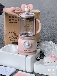 a pink hello kitty blender sitting on top of a counter next to a cardboard box