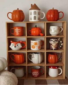 a wooden shelf filled with lots of different types of coffee mugs and pumpkins