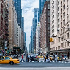 a busy city street filled with lots of traffic and people walking across the crosswalk