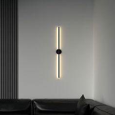 a living room with a black couch and a white wall that has a light on it